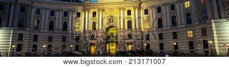 Vienna, Austria. Illuminated Hofburg Palace seen from Michaelerplatz at night in Vienna, Austria. Motion blurred people. Popular landmark in the city
