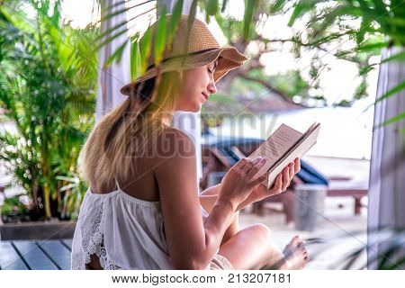 Girl Reading A Book On The Beach