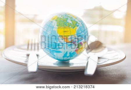 Globe model placed on plate with fork menu in famous hotels. International cuisine is cuisine that is practiced around the world often associated with specific region country.