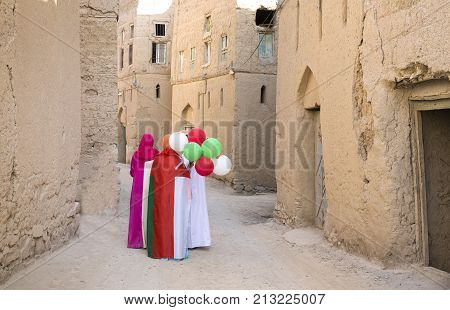 omani ladies wearing omani flags and baloons with national colors in celebration of national day