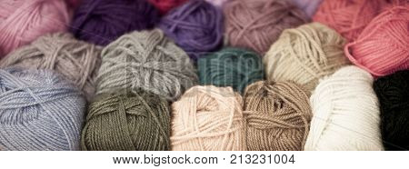 Colorful different wool thread balls. Long wide banner with shallow depth of field