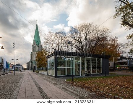 Kristiansand, Norway - November 8, 2017: One of the entrances to the new underground parking garage under the square in Kristiansand. Domkirken church in the background. Cobblestone on the ground.