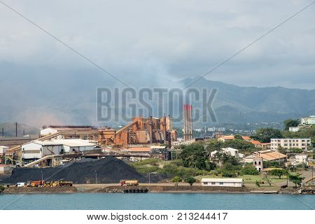 NOUMEA, NEW CALEDONIA, PACIFIC ISLANDS-NOVEMBER 25TH, 2016: SLN plant on the Pacific Ocean waterfront with smoke stacks, island landscape and cloudy skies in Noumea, New Caledonia