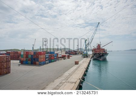 NOUMEA, NEW CALEDONIA, PACIFIC ISLANDS-NOVEMBER 25TH, 2016: Commercial port with shipping containers, nautical vessel and cranes under an overcast sky in Noumea, New Caledonia