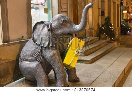 WARSAW, POLAND - JANUARY 02, 2016: Sculpture of a small elephant with a gift box around his neck near a gift shop in the historical part of Warsaw.