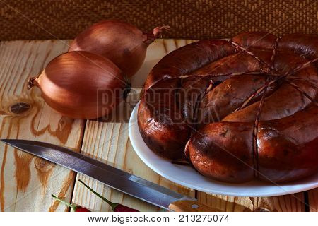 Preparation of a festive table on a table of smoked sausage a tomato onions and acute red pepper to improve apetit.