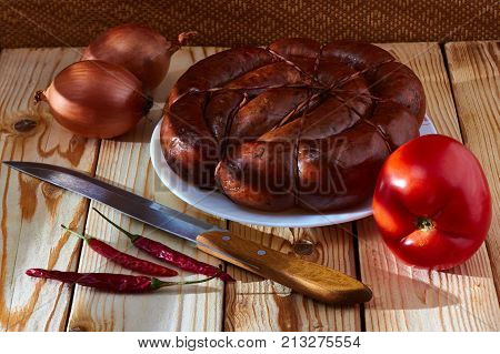 Preparation of a festive table on a table of smoked sausage a tomato onions and acute red pepper to improve apetit.