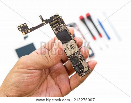 Chiangrai Thailand: September 13 2017 - Close-up image of technician hand showing Apple iPhone 6S logic board on blurred components and tools background.