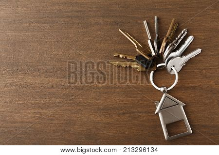 Bunch of keys on a house shaped keychain at wooden table background. Concept for real estate or renting home with copy space, top view