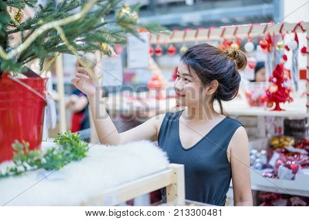 Portrait of smiling young asian woman choosing gifts and decorations at Christmas fair and new year at department store.