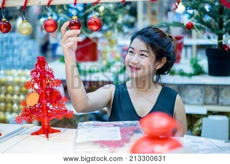 Portrait of smiling young asian woman choosing gifts and decorations at Christmas fair and new year at department store.