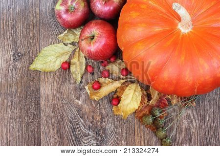 Autumn composition. Pumpkin apples and dried leaves on a wooden background.