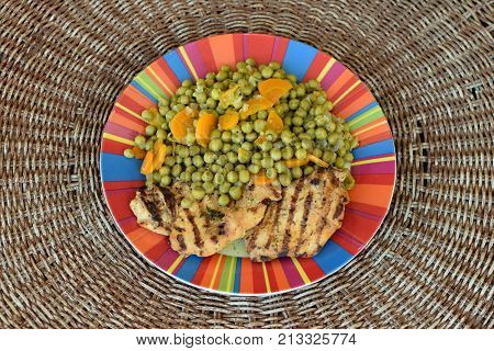 Green peas with carrots and grilled chicken fillet. Greek food.