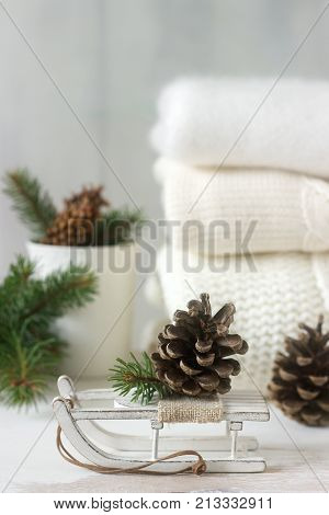 Winter Concept With White Blanket Pullover, Gloves, Sleds, Cup, Cones And Fir Branches.