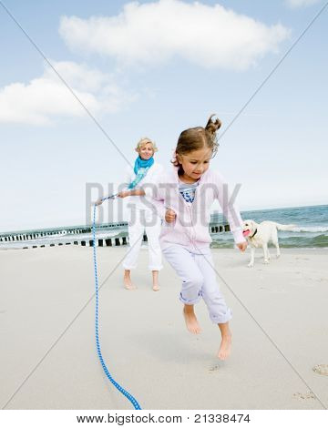 Wakacje - dziewczyna bawi sie z skakanka na plaży
