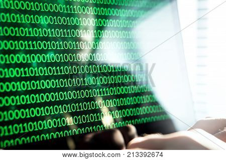 Hacker writing code with laptop computer. Binary numbers zero and one on monitor screen. Cyber security threat attack and online crime concept.