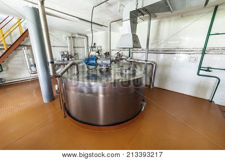 A large room with an installed metal cistern. Equipment for mixing sugar and yeast mixture.