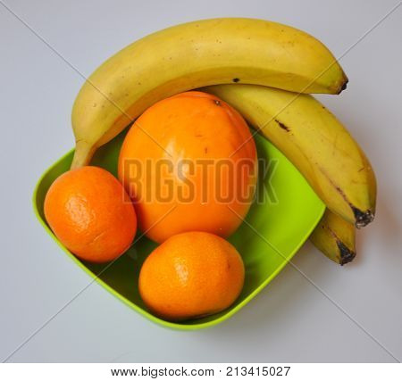 persimmon, banana, mandarin in a green toiler