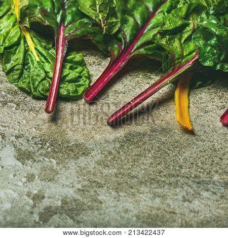 Flat-lay of fresh leaves of swiss chard over concrete stone background, copy space, square crop. Food frame. Clean eating, vegetarian, alcaline diet, organic, healthy cooking concept