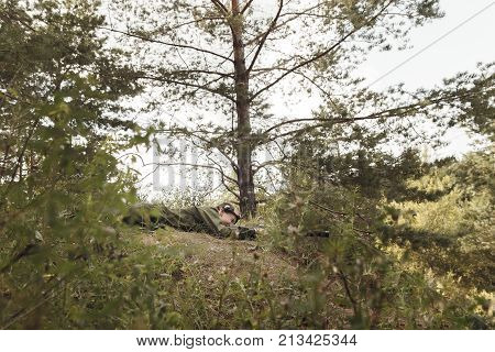 Young boy with a gun lies on the ground laser tag in open air. Lasertag shooting game. Military sport