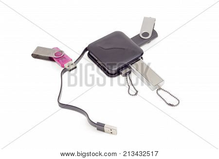 External USB hub in black square plastic casing with short cable and several different usb flash drives on a white background