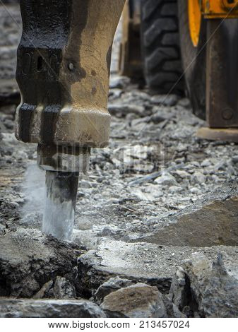 Excavator breaking and drilling the concrete road for repairing close up