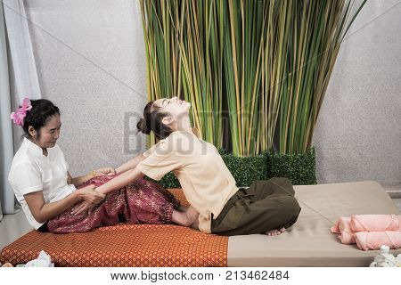 Thai Masseuse doing massage for woman in spa salon. Asian beautiful woman getting thai herbal massage compress massage in spa.She is very relaxed. Healthy Concept