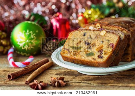 Homemade delicious soft and moist rum fruits cake or Christmas fruits cake with rich dried fruit and nuts slices on wood plate put on wood table with copy for party and celebration. Rum fruit cake for Christmas celebration ready to served.