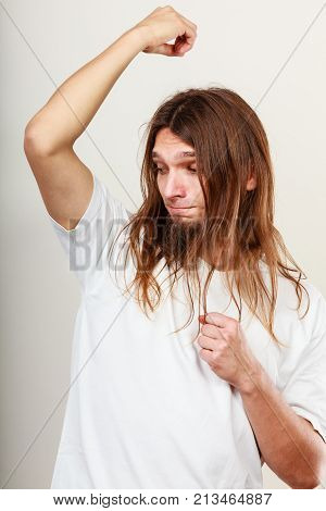 Expression of very bad smell. Young long haired sweaty man making hand gesture. Sweating concept.