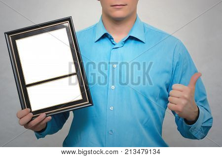 Engineer award mockup. Best worker certificate. Man holding in one hand empty blank photo frame and showing thumbs up gesture sign by another hand. Gratitude concept. Grateful letter.