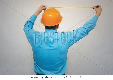 Builder worker holding in hands construction roulette and measures copy space in front of him back view isolated. Engineer takes measurements.