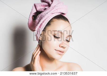young attractive girl with clean skin, with a pink towel on her head, eyes closed, smiling
