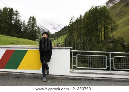 Asian Thai Woman Travel And Posing For Take Photo With Alps Mountain At Petrol Station