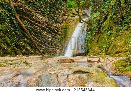 Waterfall and boulders in the ravine Chudo-Krasotka in summer day Sochi Russia