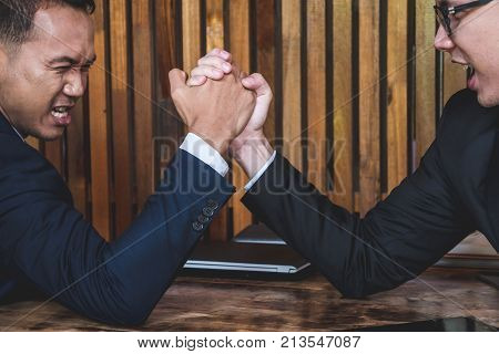 Two Businessmen arm wrestling on the desk in the office.