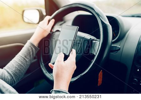 Woman using car navigation on smartphone while simultaneously driving automobile on the road