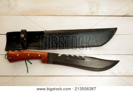 Combat Knife with Leather cover bag On white wooden background ,concept for forest adventure travel,Top view