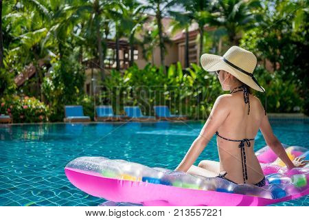 Women wearing bikini or swimware suits swimming pool sitting on a blue protrude at the resort town of Pattaya in Thailand.