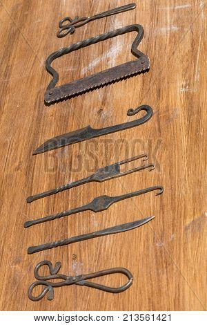 medieval surgery doctors tools on wooden table, iron shears, scissors, knife, saw and picks