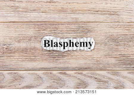 BLASPHEMY of the word on paper. concept. Words of BLASPHEMY on a wooden background.