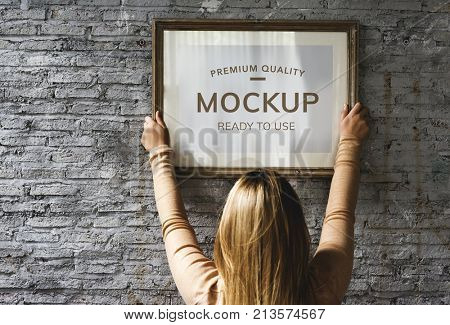 Woman hanging a photo frame mockup