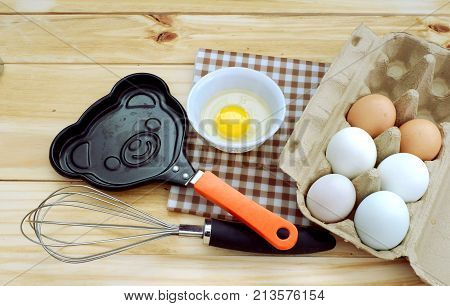 Egg carton of fresh brown eggs and cute pan on wood board,top view