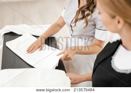 Chambermaid teaching trainee to fold towels on table