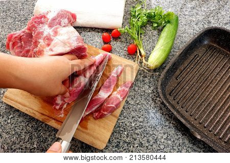 Hand cut Raw Pork  chops on wooden cutting board and knife with herb, salt, vegetable preparing to cook with flying pan dark background,top view