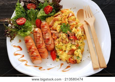 Omelette  with onion, tomatoes,sausage and fresh salad wooden spoon and fork  on white plate