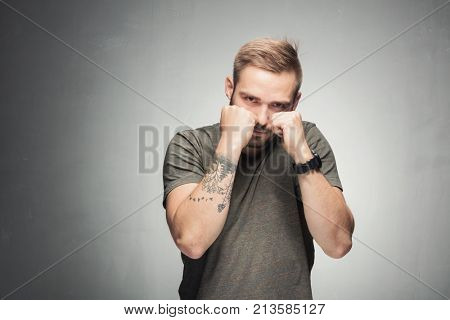 Young masculine man showing power with his fists clenched and ready to box. Angry expression.