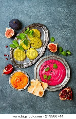 Middle Eastern traditional food. Authentic arab cuisine. Vegan green baked falafel roasted beet and pumpkin hummus. Top view flat lay overhead
