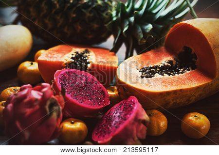 Juicy exotic fruits close up. Pineapple, papaya, mango, gragon fruit on table ready to eat