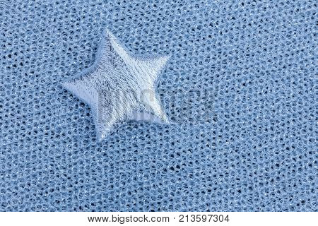Picture of a shiny silver star on a gray texture cloth