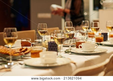 Dining table full of a variety of delicious festive food with a person setting up feast in background